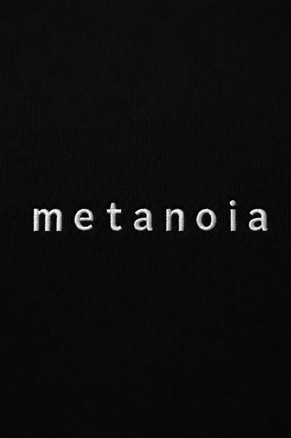 METANOIA embroidered logo detail on black hoodie