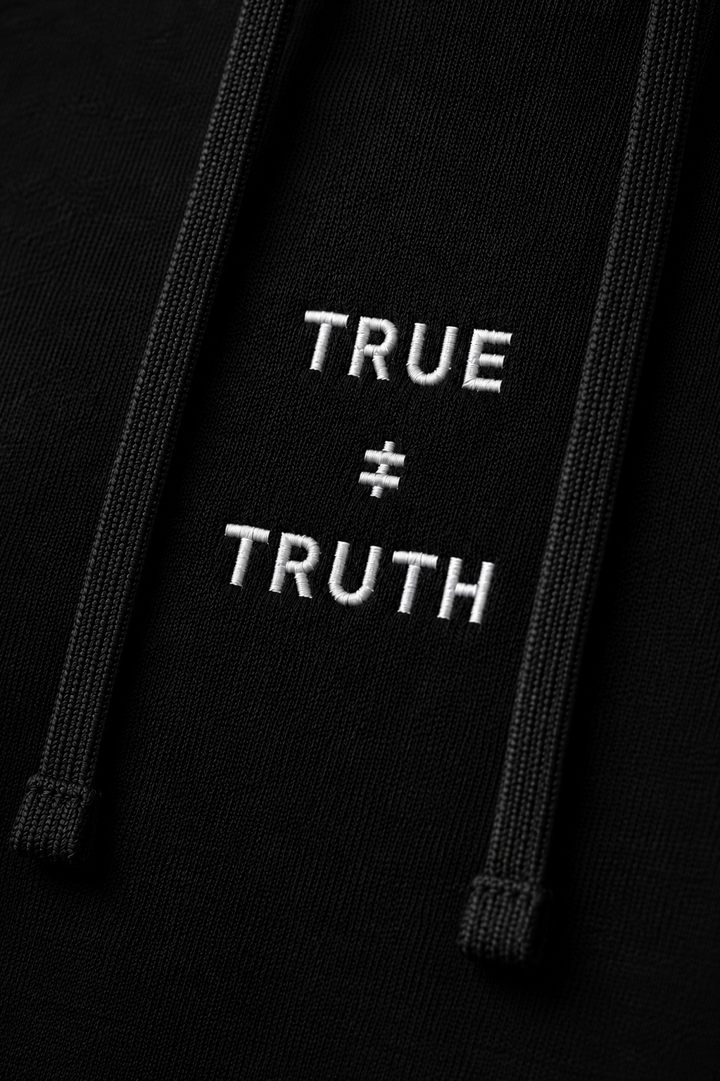 TRUE + TRUTH embroidered logo detail on black hoodie