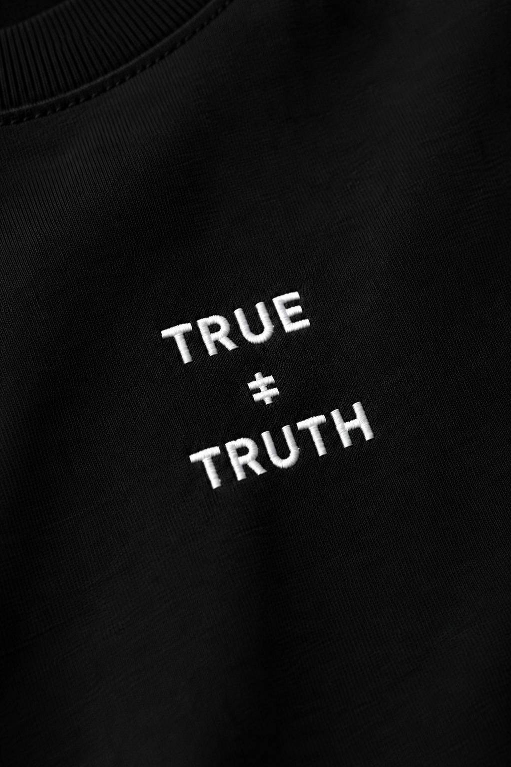 TRUE + TRUTH embroidered logo detail on black tee