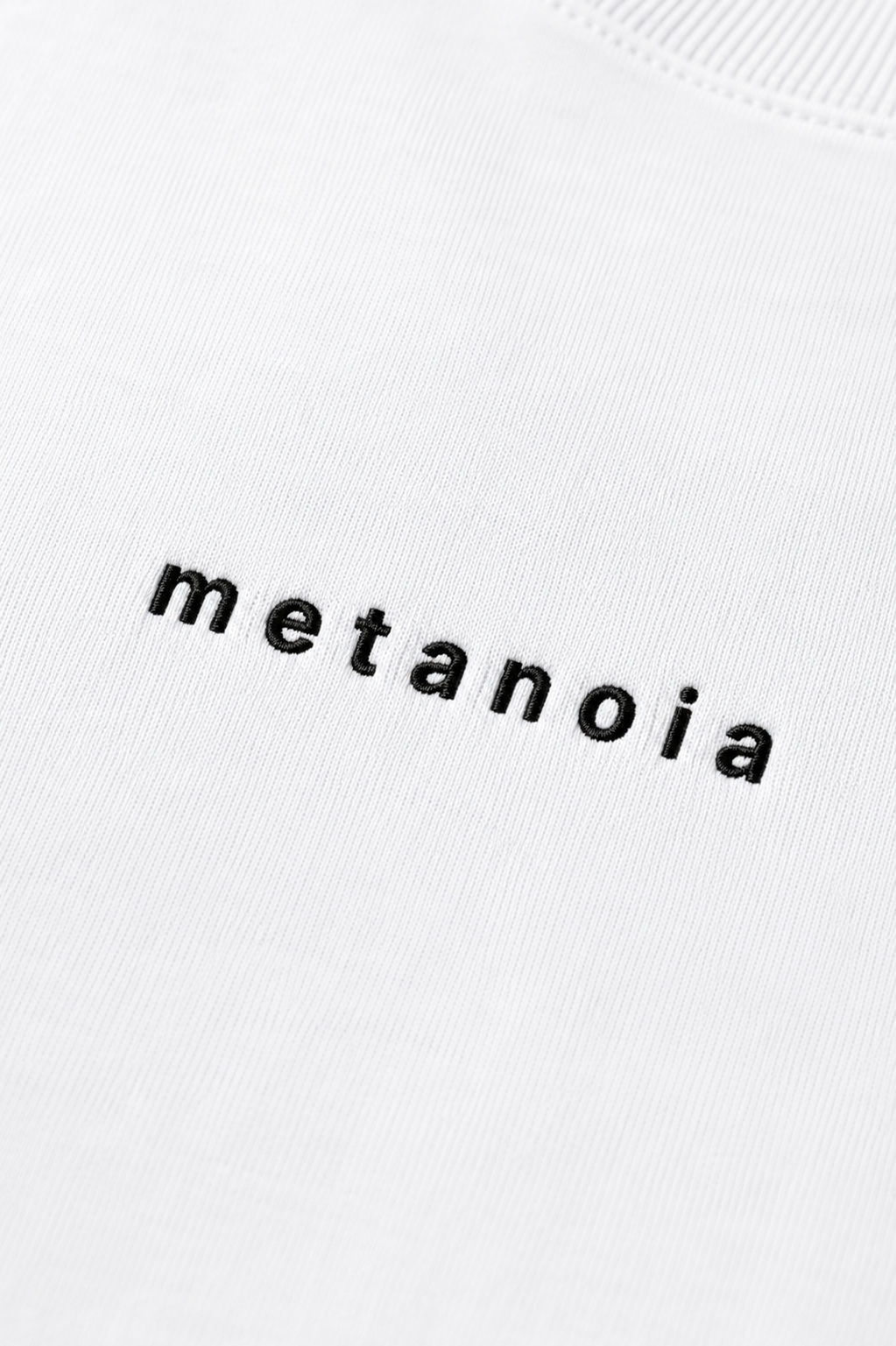 METANOIA embroidered logo detail on white tee