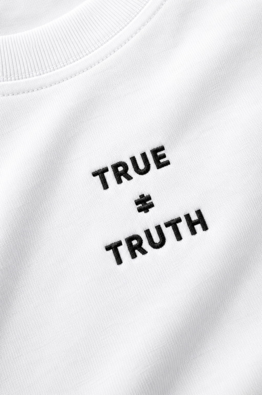 TRUE + TRUTH embroidered logo detail on white tee